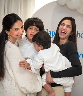 Two women laughing with a child at a birthday party