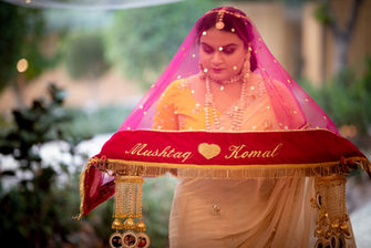 Bride under a red wedding canopy held over her