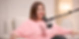 Mujer con jersey rosa hablando en un micrófono de podcast