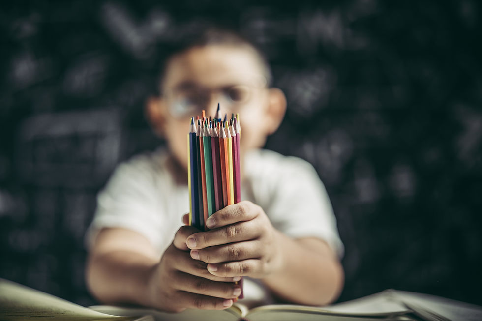Criança com óculos segurando lápis de cor em ambiente escolar, representando aprendizagem, infância e cultura escolar.