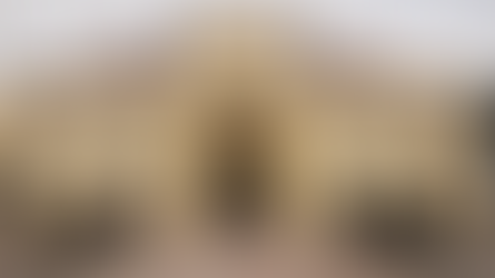 Front exterior of The Barrett School building in Destin, Florida, with arched entryway and landscaped walkway.