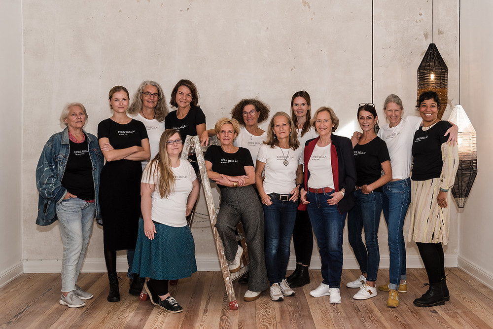 Dreizehn Frauen aus Wirtschaft, Kultur und sozialen Engagement stehen für ein Gruppenfoto beisammen um ein T-Shirt zu bewerben