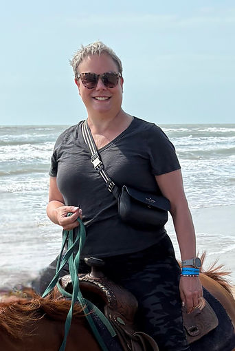 A photo of Executive Coach, Christine Lloyd-Newberry, on horseback with the ocean in the background.