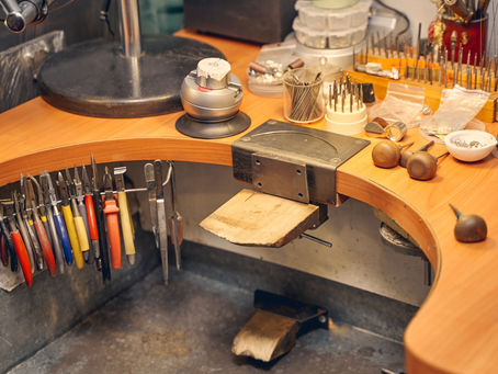 A clearly arranged workbench with tools and materials for jewelry making.