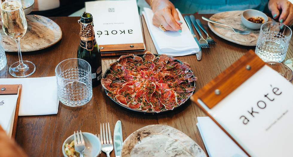 Gezellig gedekte restauranttafel met een gerecht van dungesneden vlees, champagnefles en glazen, met menukaarten