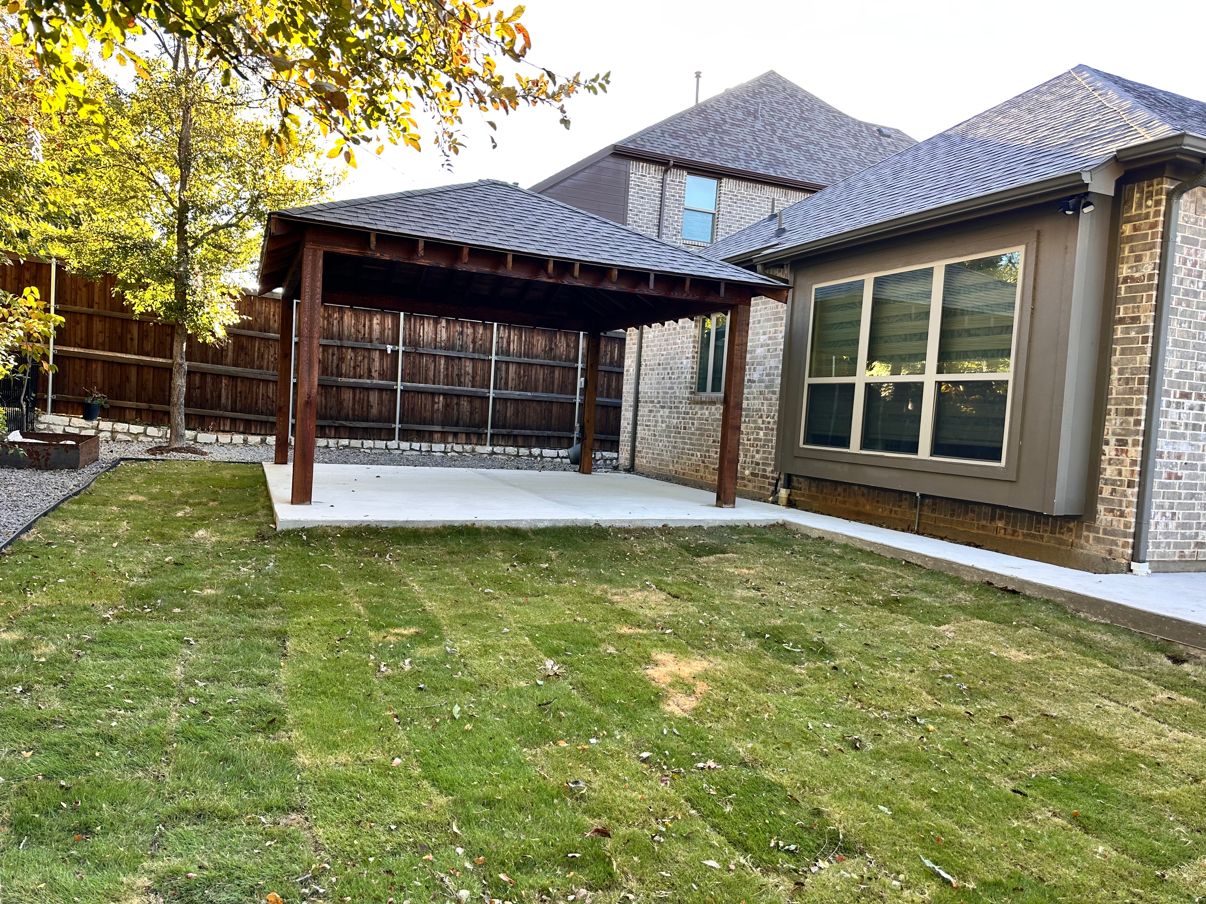 Covered wood pergola over a patio with new sod by Grayscape Landscape & Design, a landscaper in McKinney, TX