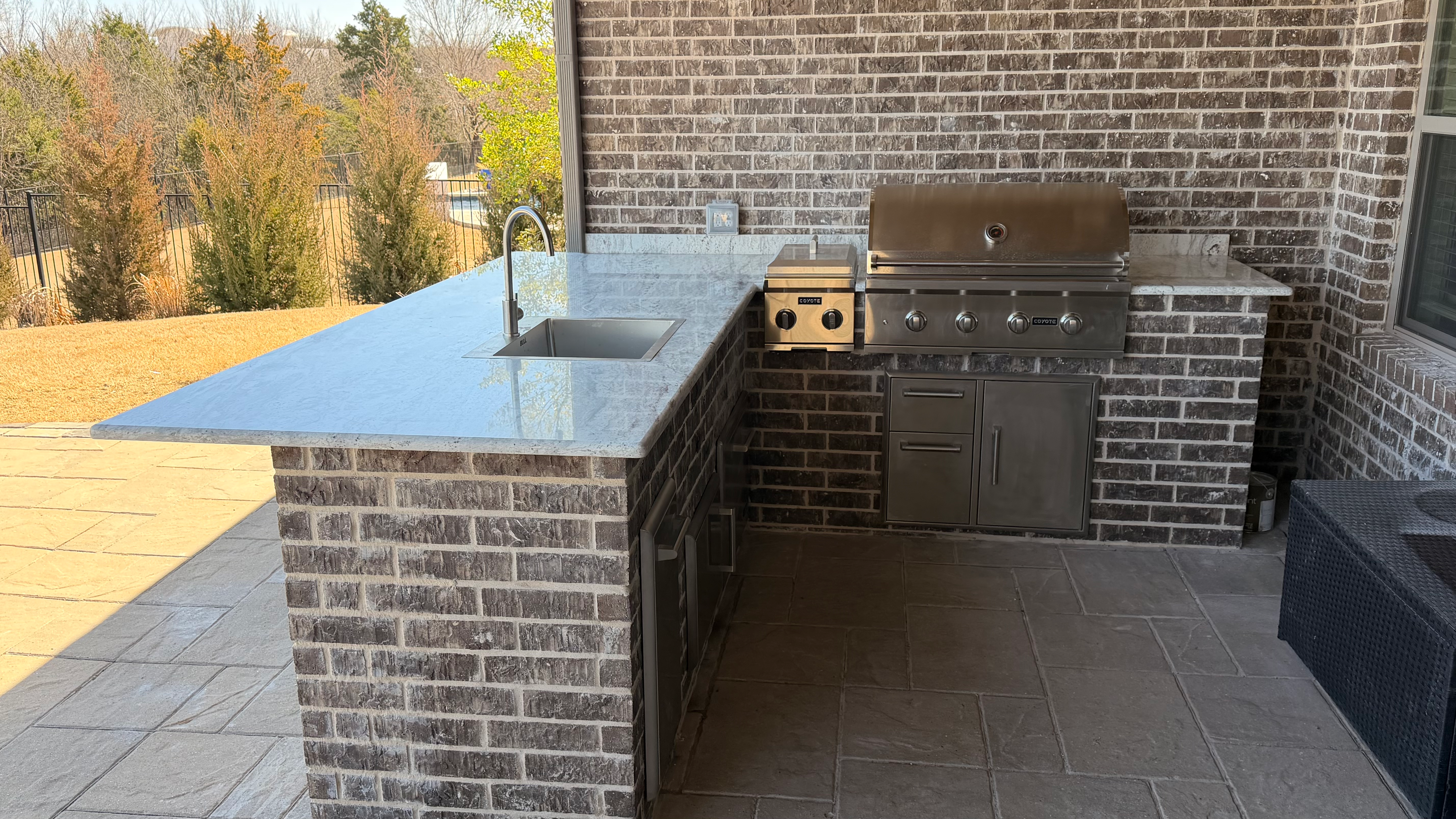 Brick outdoor kitchen with a granite counter by Grayscape Landscape & Design, Collin County, TX. Landscaper Near Me.
