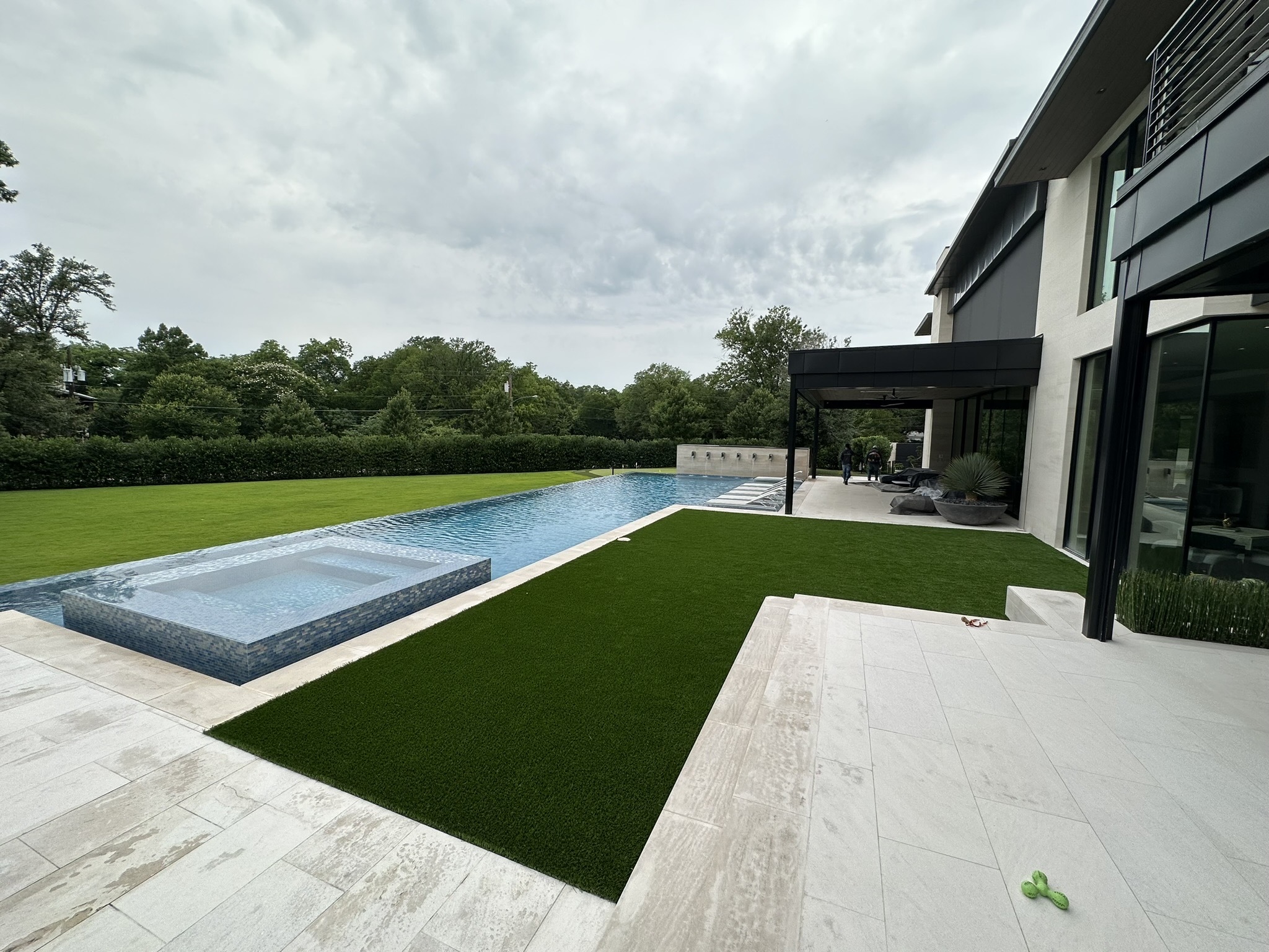 Pool with artificial turf and a concrete deck by Grayscape Landscape & Design, a landscaper in Frisco, TX