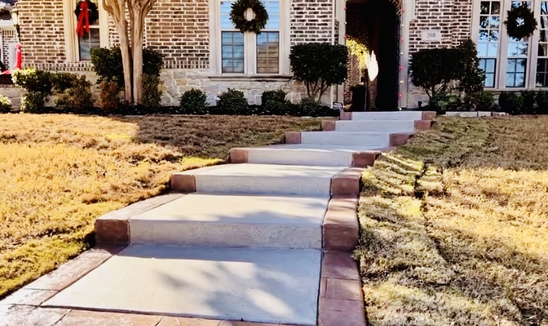 Brick-edged concrete front walkway to a brick home by Grayscape Landscape & Design, a landscaper in Lakewood, TX