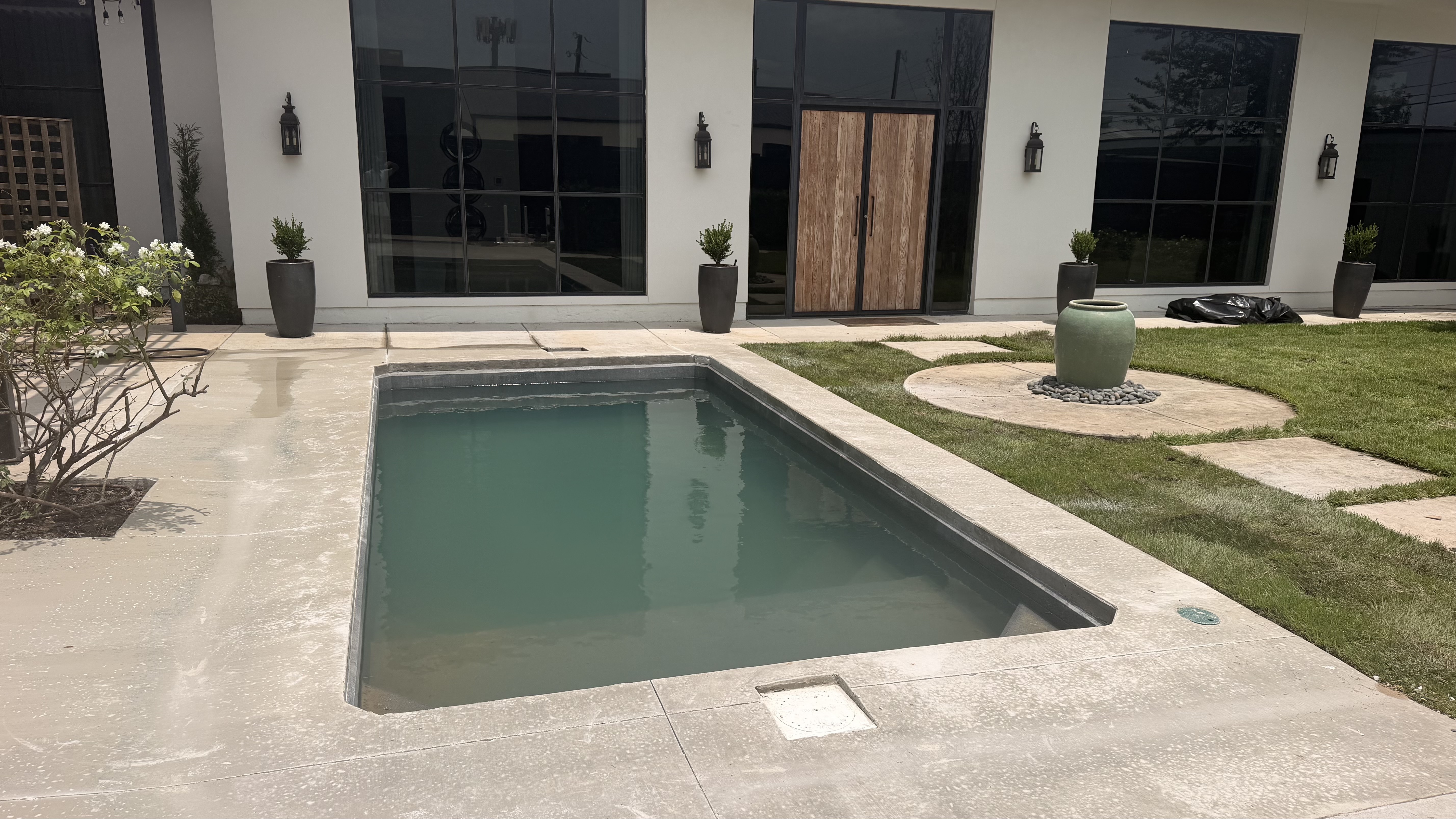 Plunge pool with a concrete deck and lawn by Grayscape Landscape & Design, a landscaper in Preston Hollow, TX