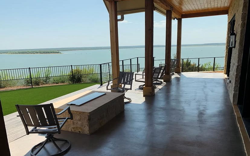 Covered patio with a fire table, turf and lake view by Grayscape Landscape & Design, a landscaper in Plano, TX