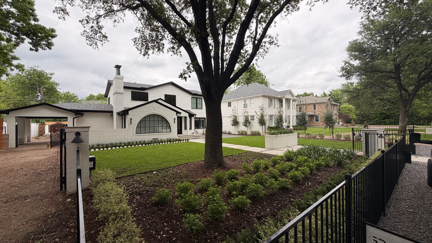 St. Augustine sod lawn under a mature shade tree with new mulched planting beds and black iron fencing in Dallas