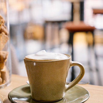 Eine Tasse Cappuccino mit Schaum auf einer Untertasse, die auf einem Holztisch steht.