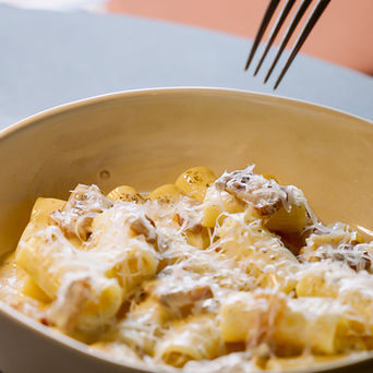 Eine Schüssel Rigatoni mit geriebenem Käse, über der eine Gabel schwebt.