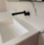 white, square basin with linear free flowing waste and black wall mounted tap.