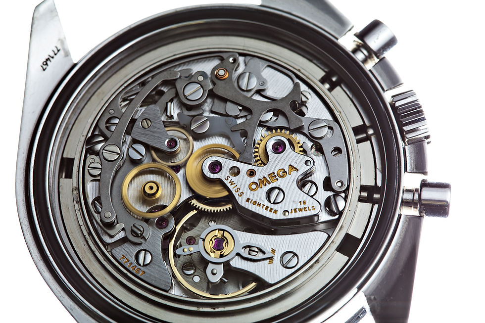 Close-up of an Omega calibre 1861 hand-wound chronograph movement inside a steel watch case, showing gilt gear-train wheels, steel chronograph levers, ruby jewels and the balance wheel with its hairspring against a white background.