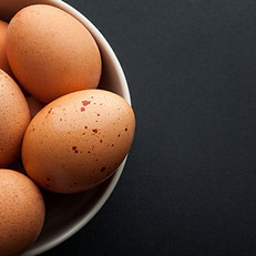 a white bowl full of brown hen's eggs