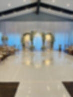 Indoor ceremony with metal wedding arch, full drapes and vinyl dance floor in Maryland