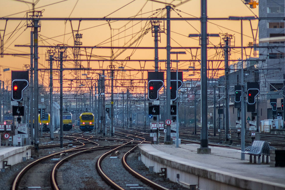 Bahngleise, Stromleitungen und Signalanlagen in einer urbanen Umgebung bei Sonnenuntergang – Symbol für Energieinfrastruktur, Stromversorgung und moderne Energienetze.