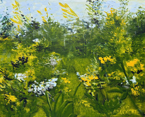 Blue and yellow wildflowers in a field with the woods in the distance.