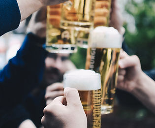 hands holding full beer glasses