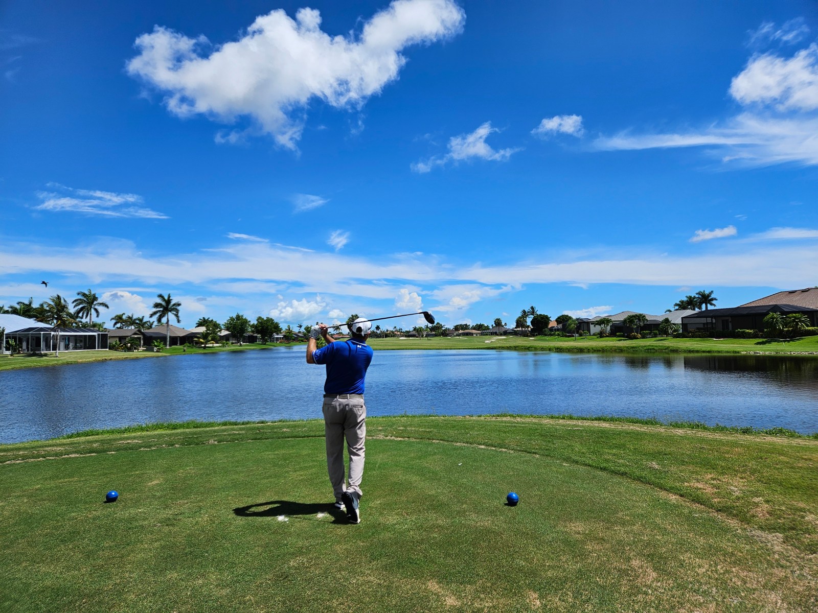 A golfer driving over a lake at Cape Royal Golf Club