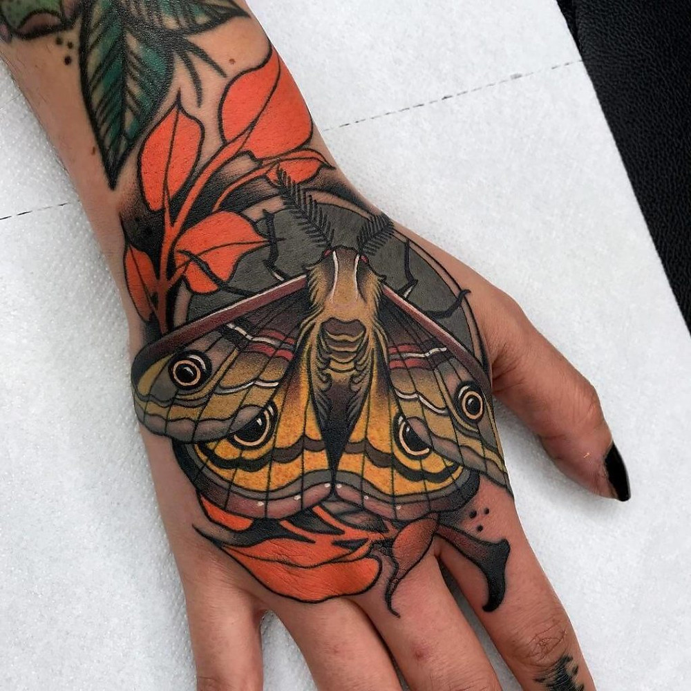 colourful moth tattoo on hand