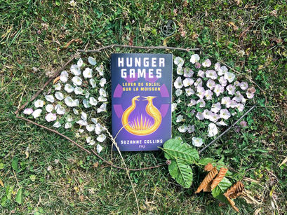 Livre Hunger Games Lever de soleil sur la moisson posé sur l'herbe