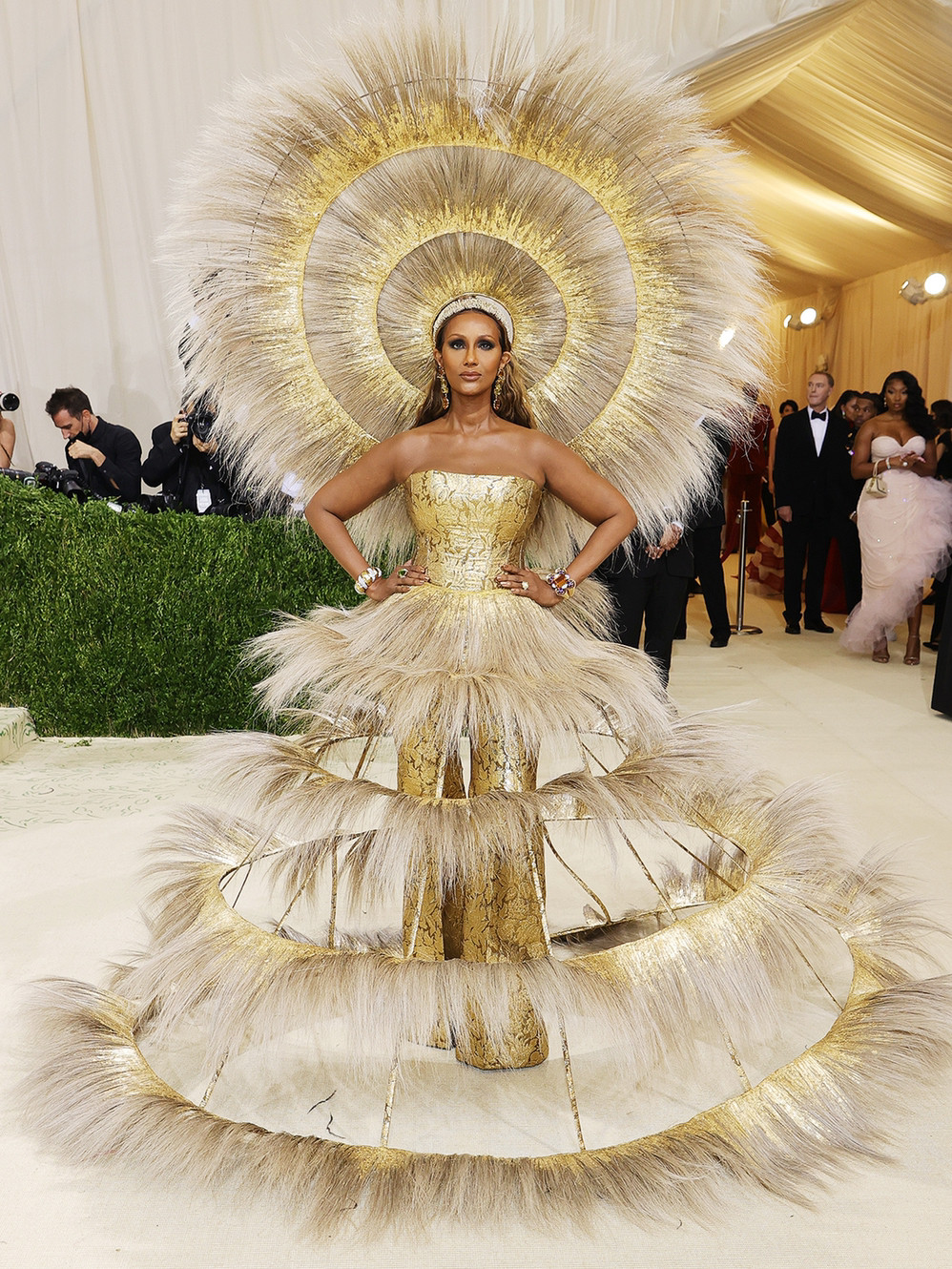 Iman wears a golden feathery dress and headpiece.