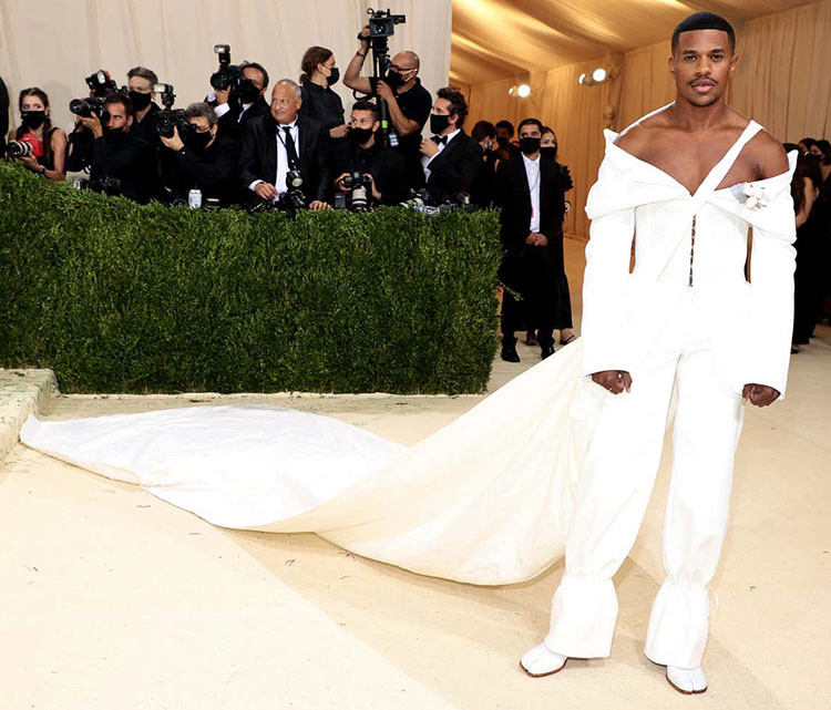Jeremy posing with his cotton cape against the floor, matching his all white outfit.