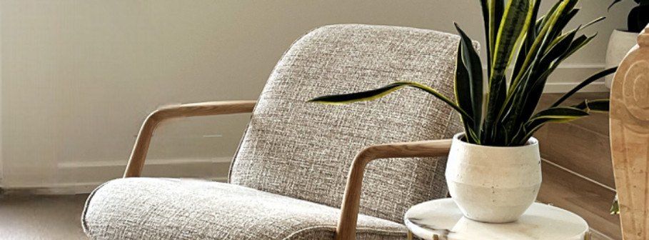 Cosy chair, styled in a living room with side table and plant.