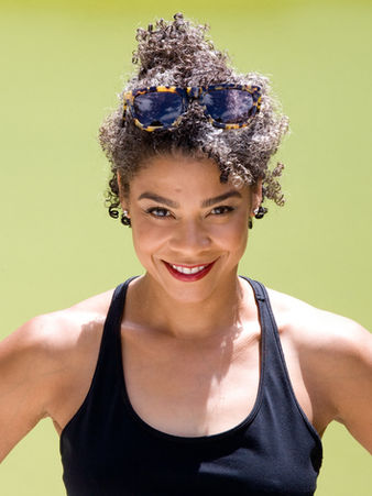 Acting Portfolio headshot of woman smiling with black curly hair wearing red lipstick and a black sports top acting headshots by Alise Black Studios