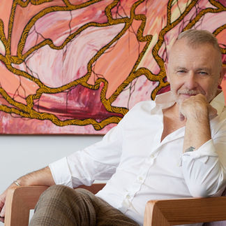 man in white shirt sitting in front of colourful painting by alise black studios
