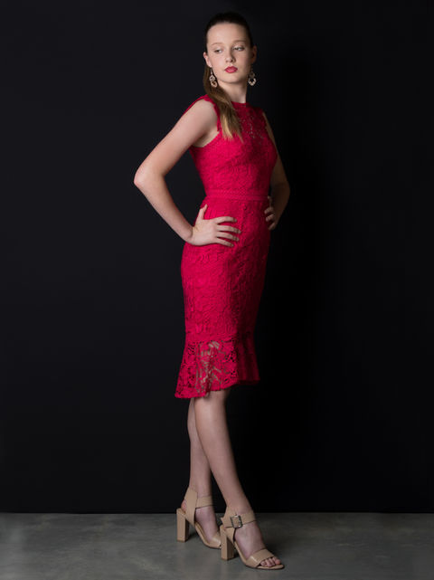 Artist Photography of a girl with her hair pulled back, posing with her hands on hips whilst standing in front of a black photo studio backdrop, wearing a red knee length dress and bright red lipstick. By Artist Photographer Alise Black Studios