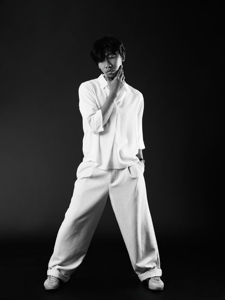 male model photoshoot of a man with white clothing on and dark hair looking down in a fashion look by Alise Black Studios
