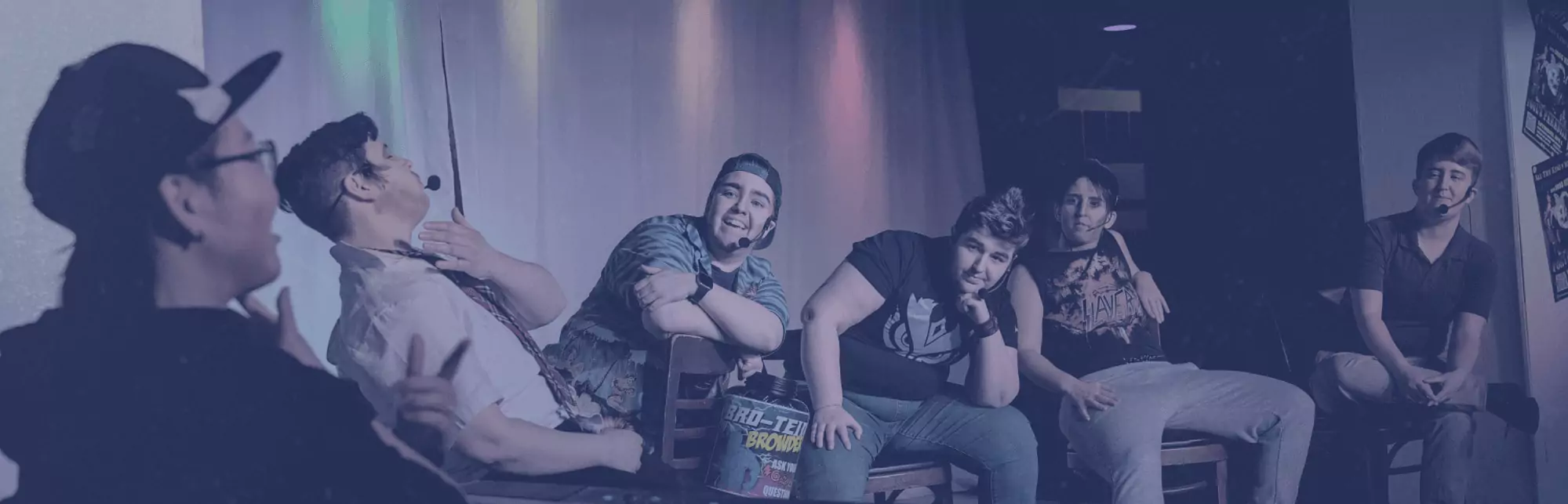 A group of drag kings chat on stage.