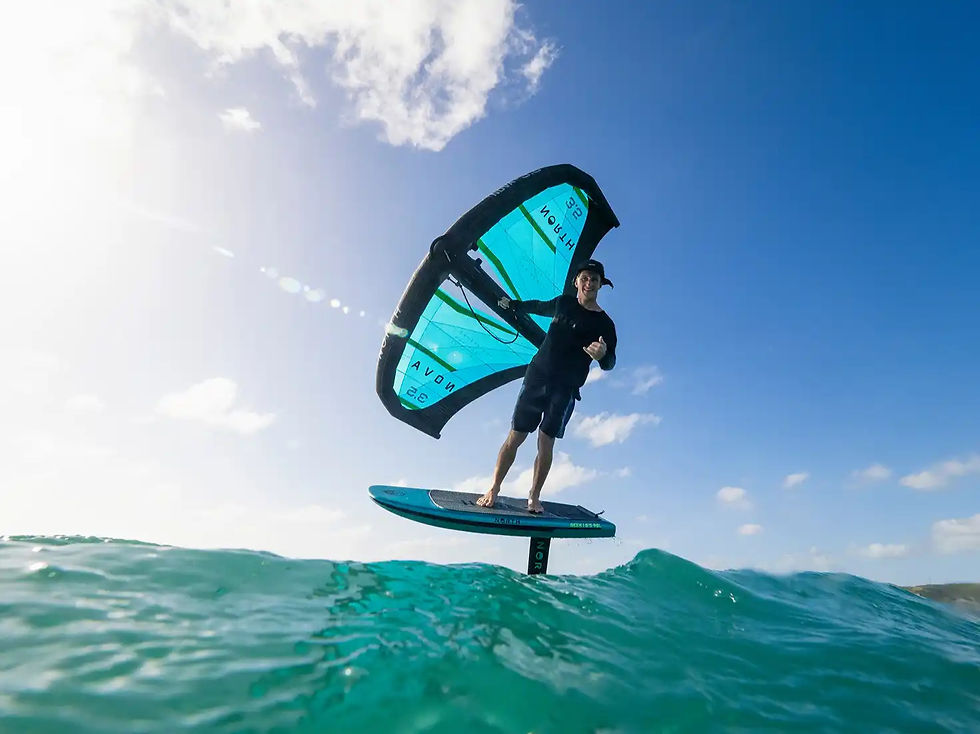 Person wingfoiling over emerald blue water smiling at camera_edited.jpg