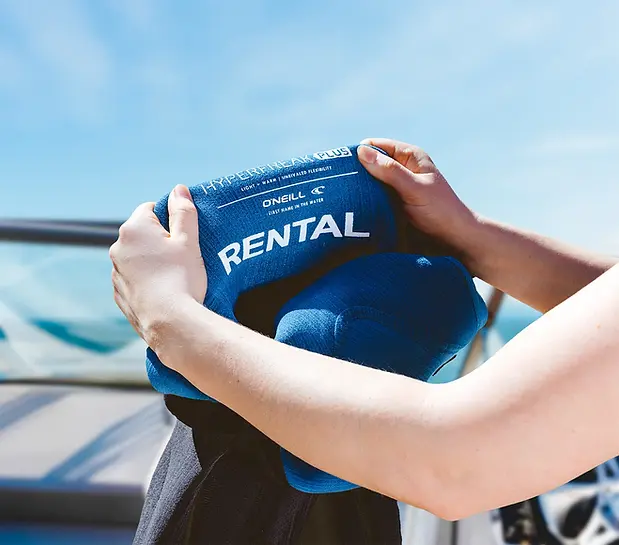 Rental wetsuit being put on with boat background Victoria copy.webp