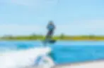 Man surf foiling behind boat during wingfoiling lessons .webp