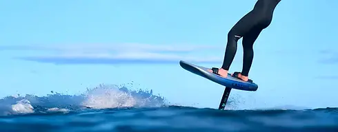 Person foilboarding above the ocean surface wearing a black wetsuit, riding a North foilbo