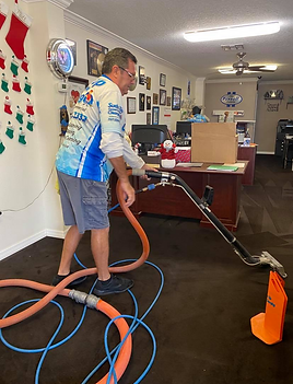 Technician from Suds Up Carpet Cleaning performing professional carpet cleaning at Team Farrell’s office in Port Richey, Florida using hot water extraction to remove dirt and restore carpet appearance.