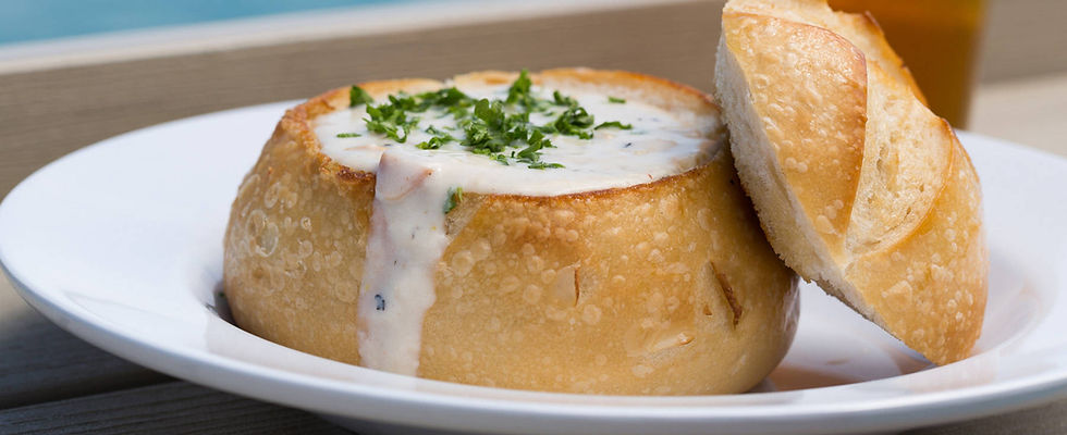 Bread bowl of clam chowder with pint of beer in the background