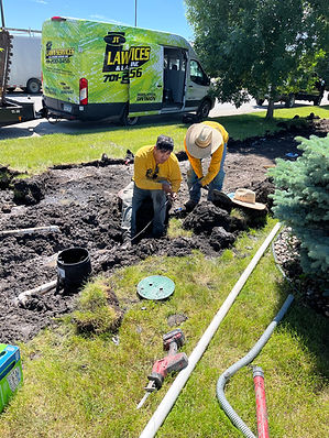 two JT Lawn Services technicians repairing a sprinkler line for the city.