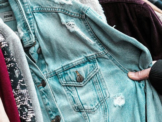 Person examining clothing on a rail in a second hand store