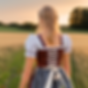 Mädchen mit Dirndl auf einem Feld im Sonnenuntergang