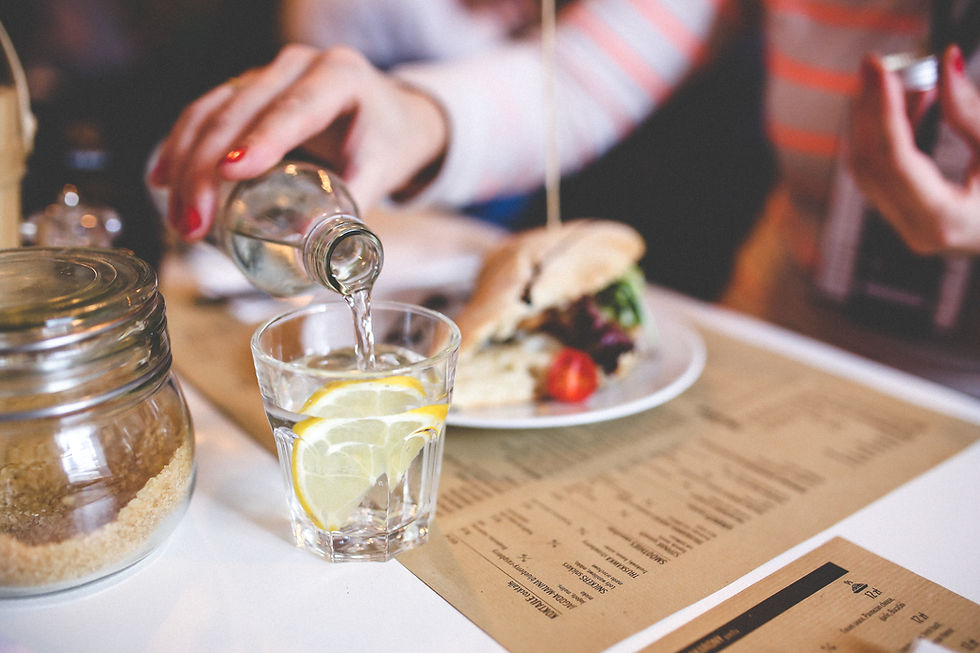 Image of a lady pouring water into a glass whilst eating in a restaurant