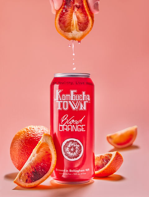 Product photography of a kombucha can with fruit being squeezed in a studio setup for advertising campaign