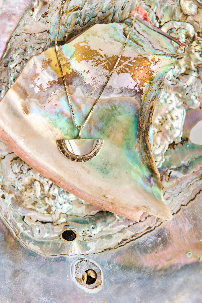 Detailed product image of sustainable jewelry featuring an iridescent abalone shell design by Young in the Mountains.