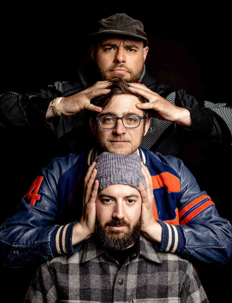 Three men stacked, hands on heads and ears