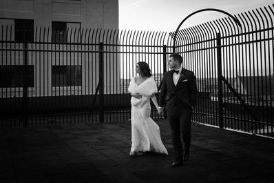 bride and groom walking on a Buffalo rooftop surrounded by iron gate